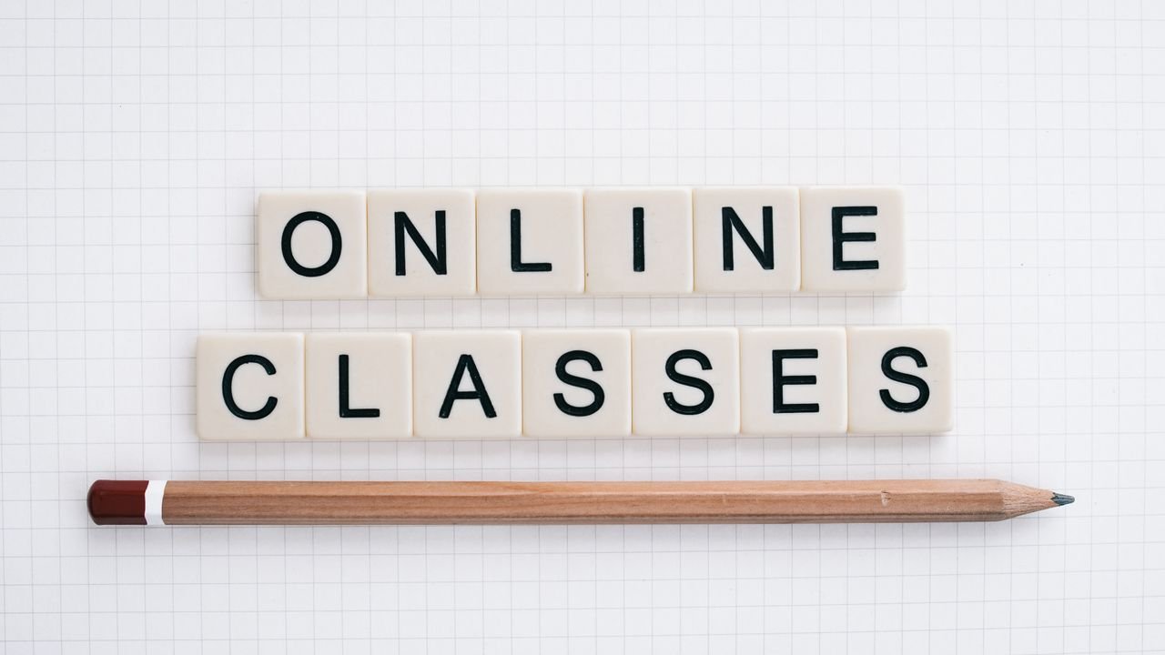 Flat lay of Scrabble tiles spelling 'Online Classes' with pencil on grid paper background.
